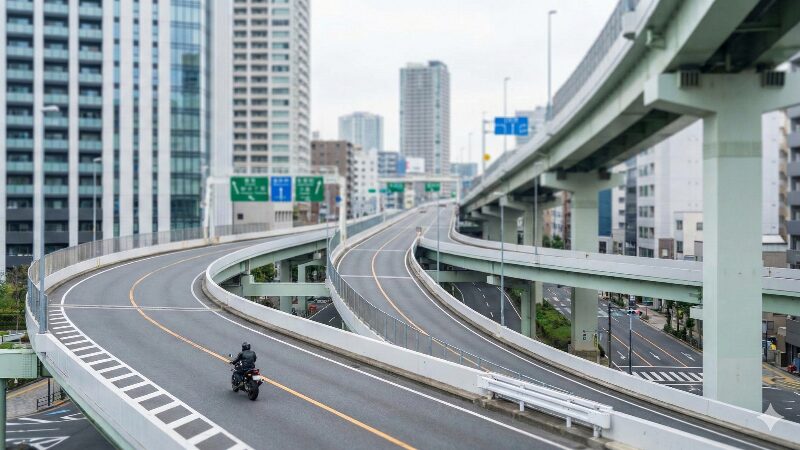 首都高の複雑なジャンクションを走行するバイクと都会の街並み