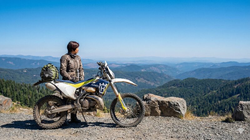 山深い林道の峠で休憩する日本人ライダーとハスクバーナTE250i