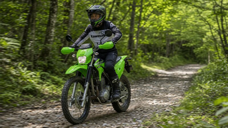 森林の林道をKLX230で走る男性ライダー