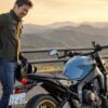 XSR900のシートが痛いと腰に手を当てるライダーと停車中の車両